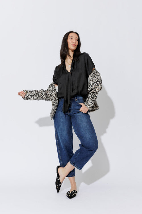 Elevated black silky tie collar shirt over leopard sleeves, cuffed denim, shown full-length and in detail.