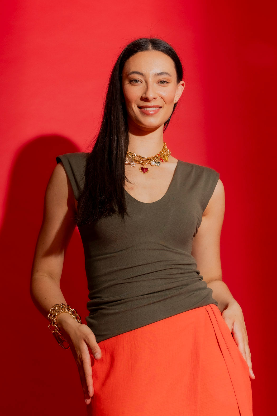 Forest Tencel Lust Cami in deep olive, styled with gold chain jewellery against a red backdrop, effortlessly elevated.