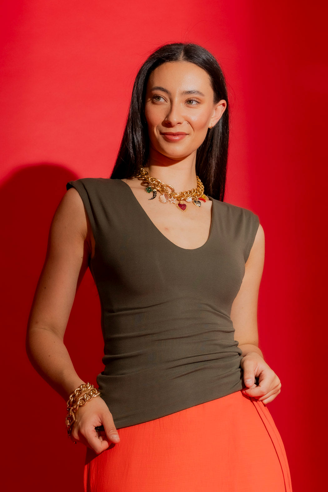 Forest Tencel Lust Cami in deep earthy green, scoop neck and sleeveless cut, styled with gold jewellery against red backdrop.