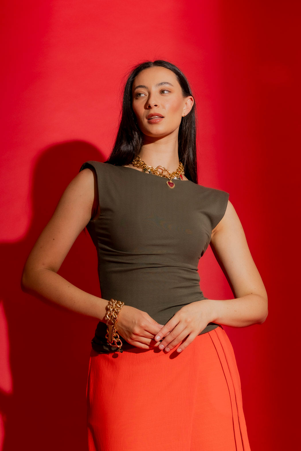 Forest Tencel Lust Cami in deep earthy green, styled with gold chain against a bold red backdrop.