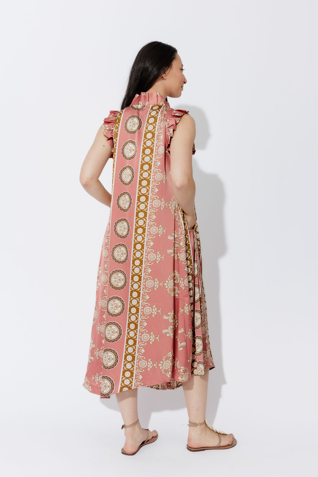 Coral Ruffle Maxi Dress in side profile, revealing the ruffled neckline, sleeve frills and a flowing printed A-line hem.