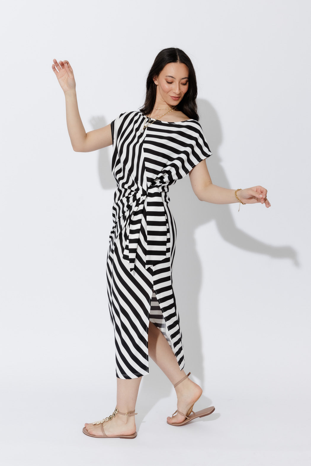 Bold Stripe Harlow Dress in fluid black-and-white stripes, tie-front waist and midi silhouette, styled with tan flats.