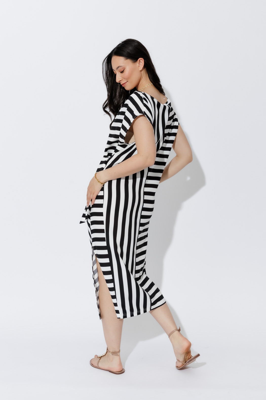 Bold Stripe Harlow Dress in a fluid black-and-white stripe, shown in a side profile with a chic side slit and effortless drape.