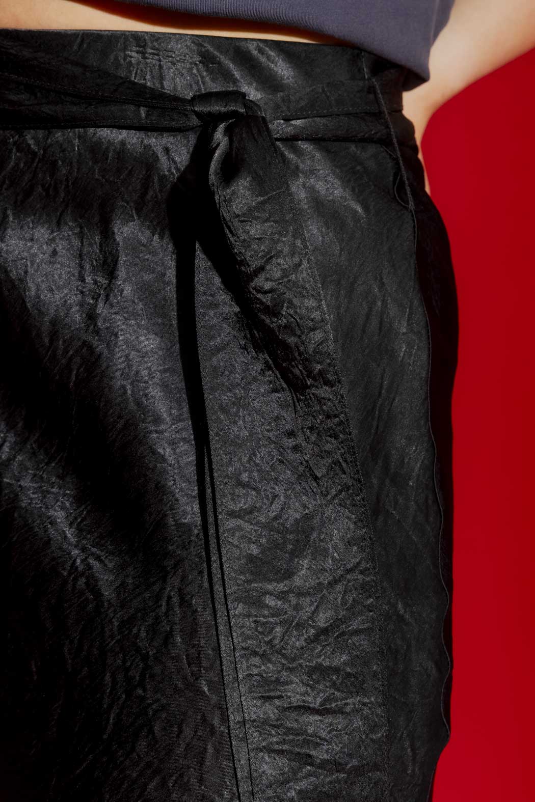 Close-up detail of the Black Bias Belted Skirt, showcasing the knotted self-fabric tie and lustrous crinkled satin.