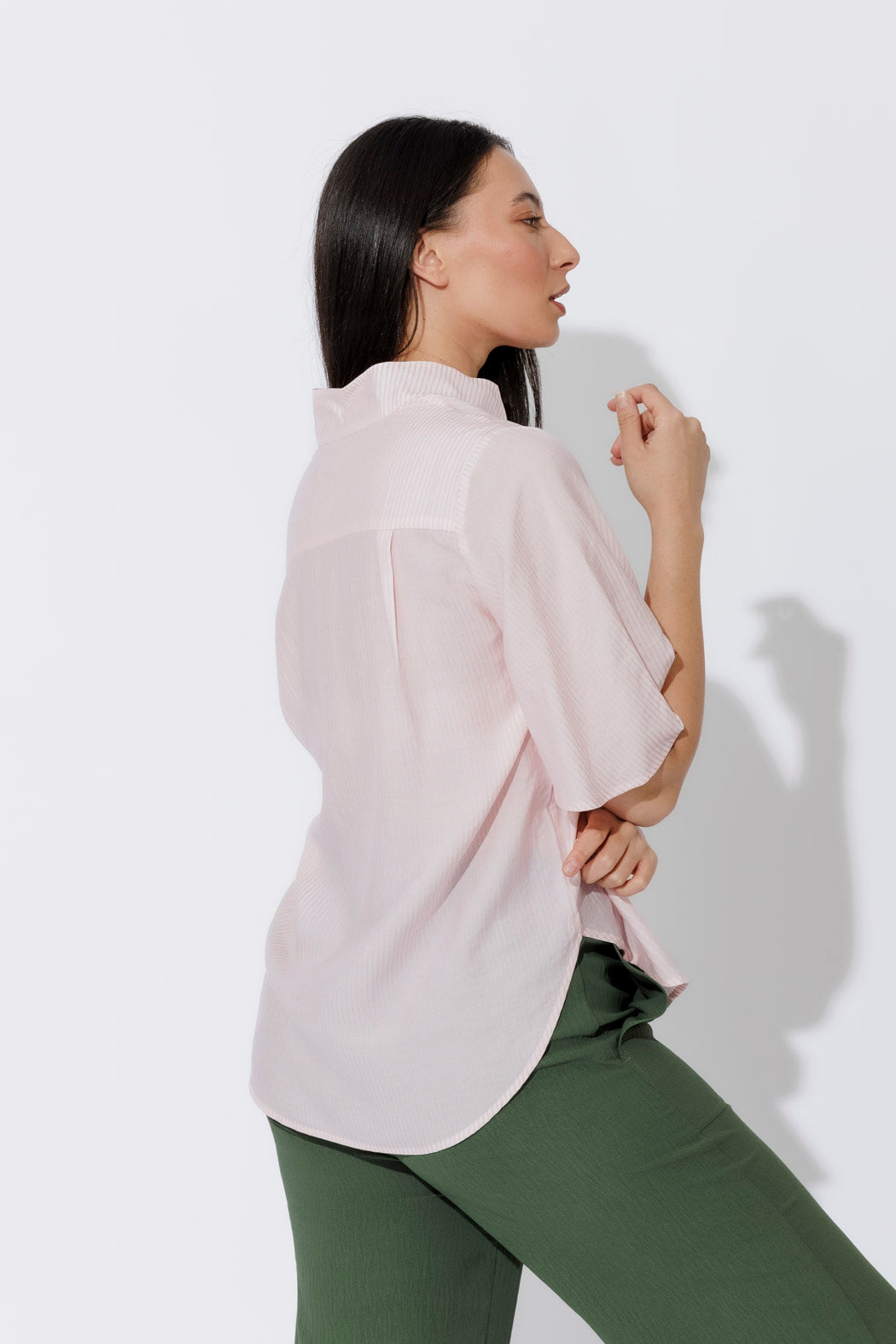 Pink pinstripe fluted shirt in relaxed side profile, stand collar and soft drape styled with olive trousers.
