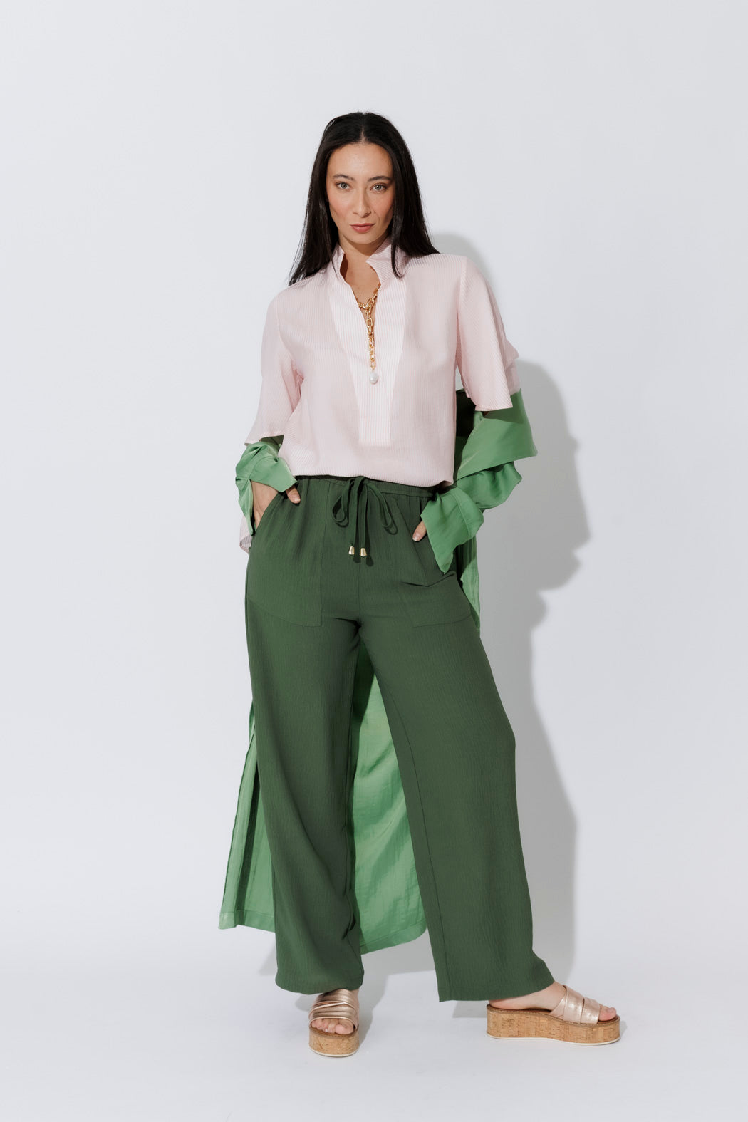Effortless Pink Pinstripe Fluted Blogger Shirt layered over green, styled with olive trousers, front view.