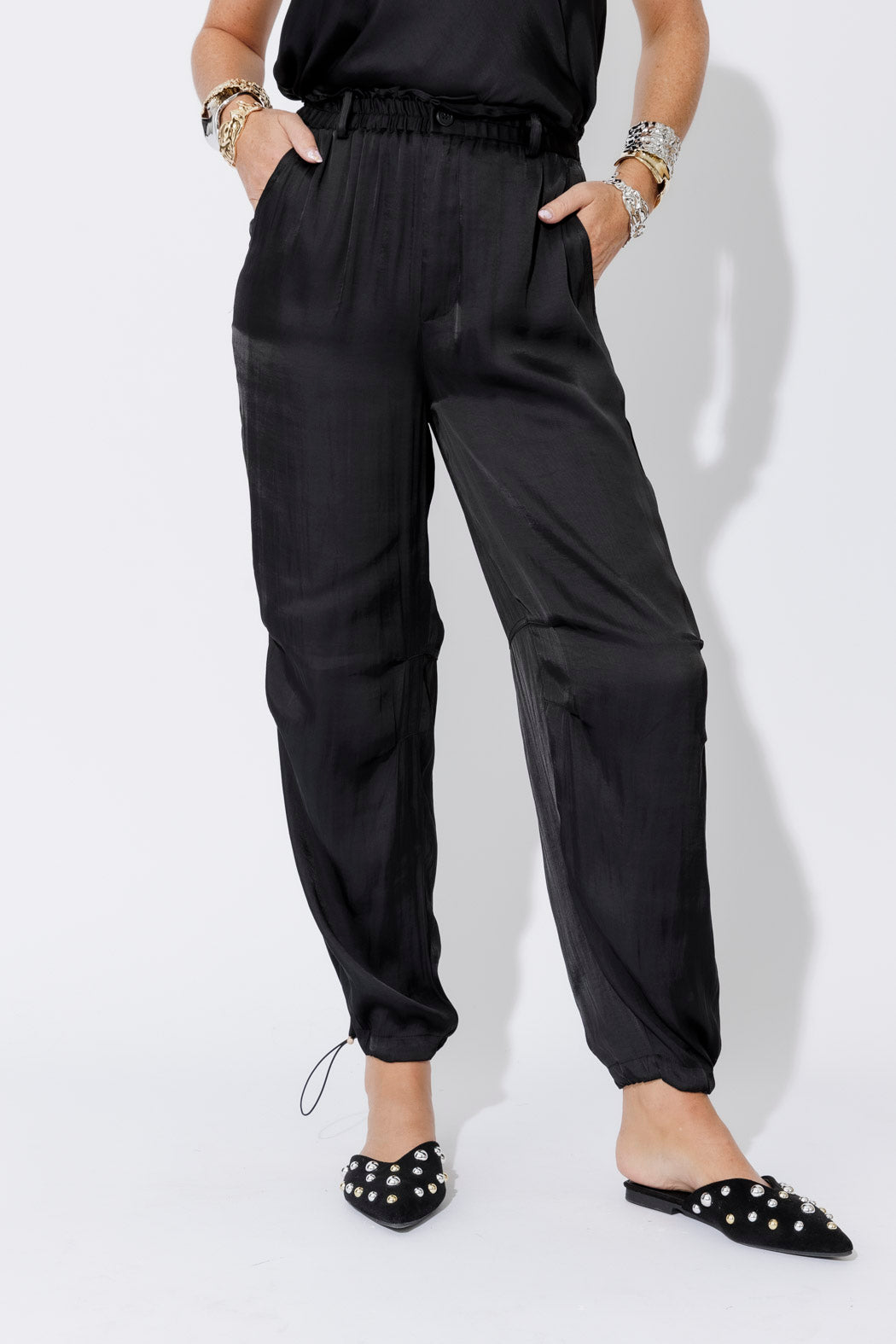 Black Glow Shell Pant in full-length and close-up views, showing smocked waist, silky shell drape and ankle drawstring cuff.