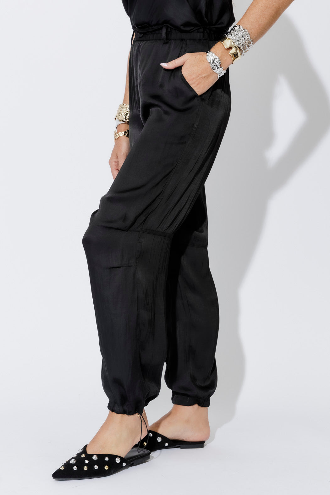 Black Glow Shell Pant, relaxed ankle-grazing cut with silky drape and gathered hem, styled with studded mules.
