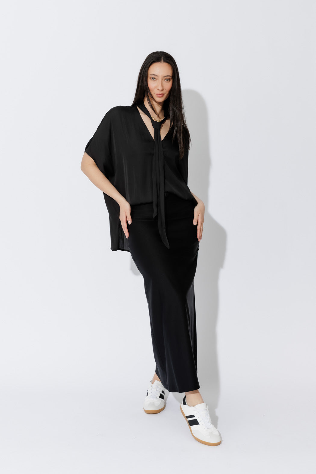 Model showcases the Black Tie Bondi Top in an oversized silhouette, V‑neck and long side ties, draped with a stepped hem.