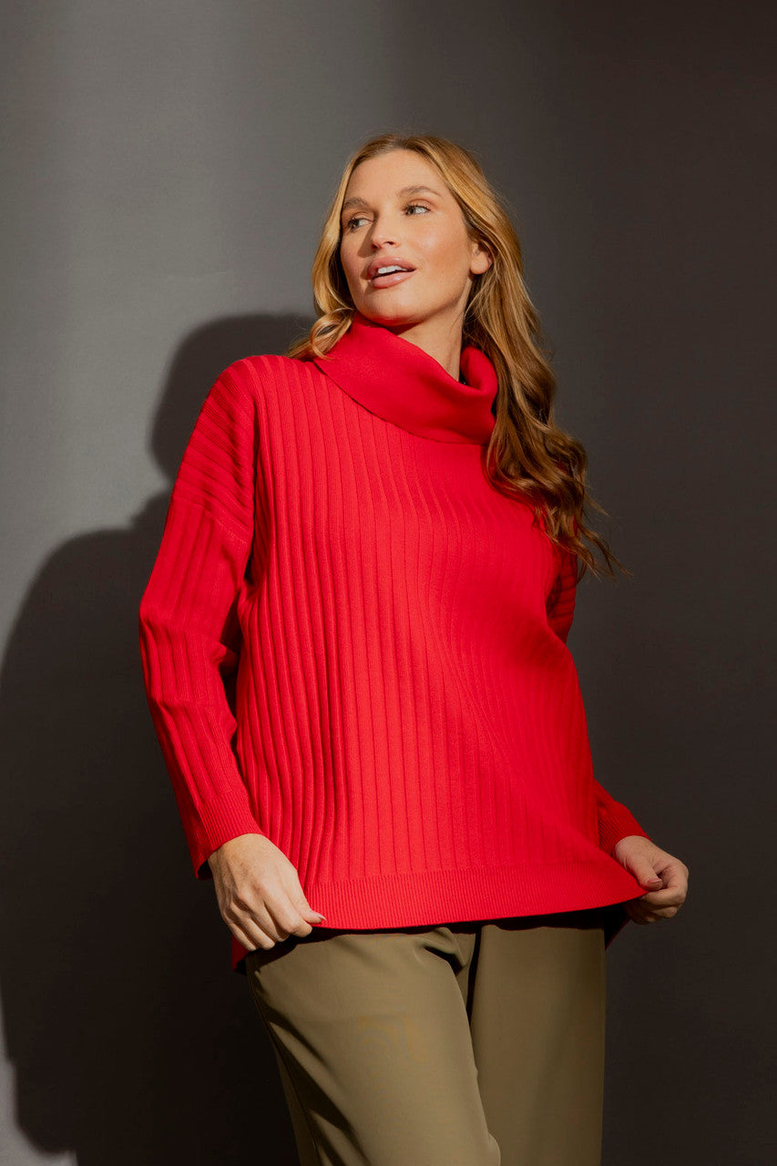 Effortless red ribbed cowl neck jumper in a relaxed silhouette, styled with olive trousers on a grey studio backdrop.
