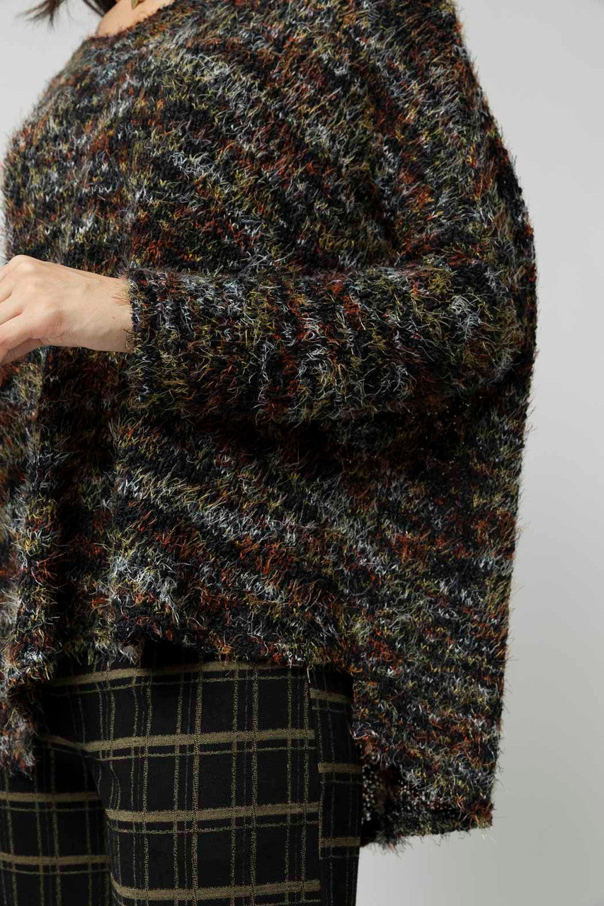 Detail shot of the fluffy speckle knit jumper, its elevated texture and hi-lo hem styled effortlessly over plaid trousers.