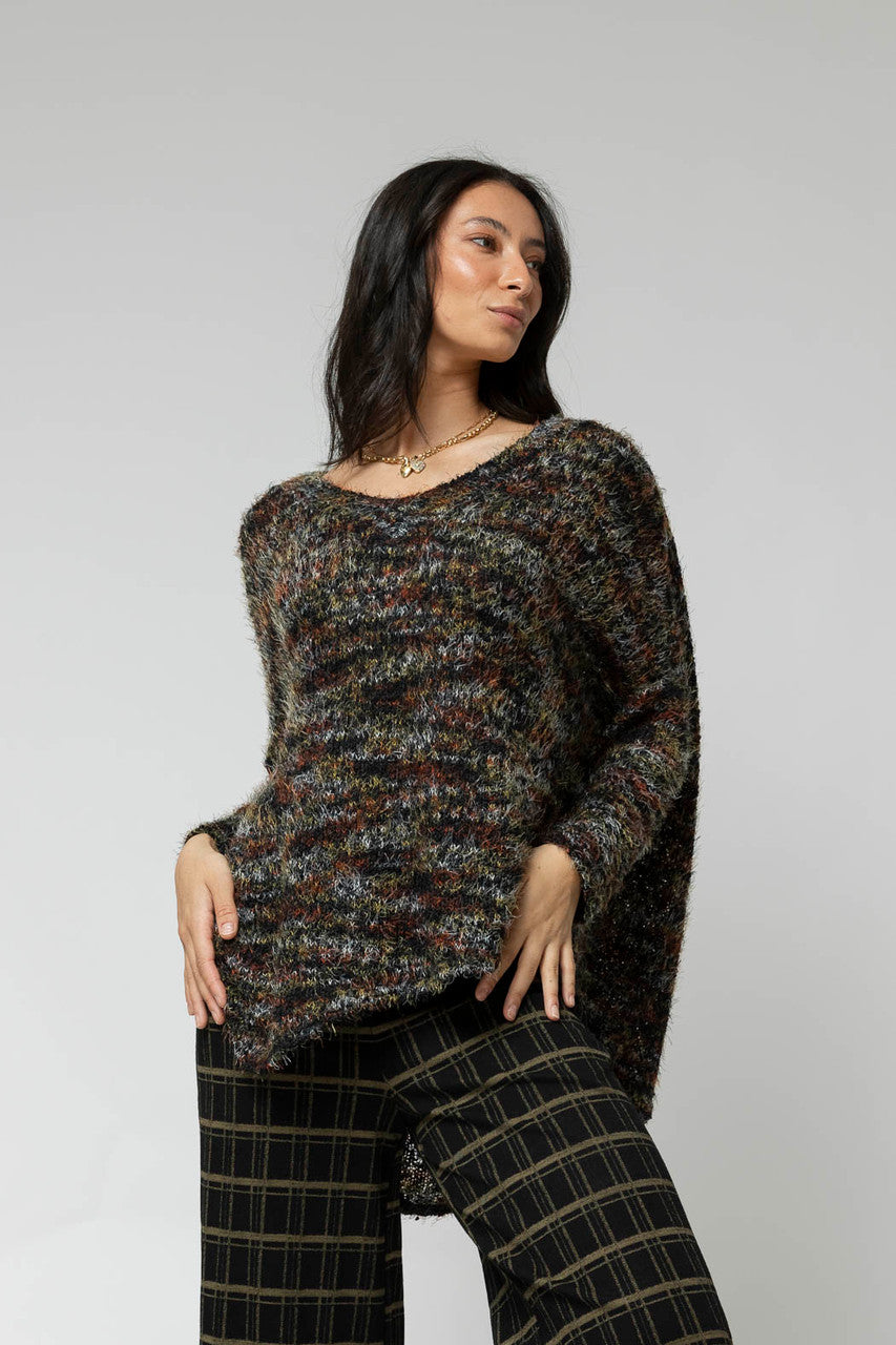 Effortless black speckle fluffy V-neck jumper, relaxed fit styled over plaid trousers, hi-lo hem.